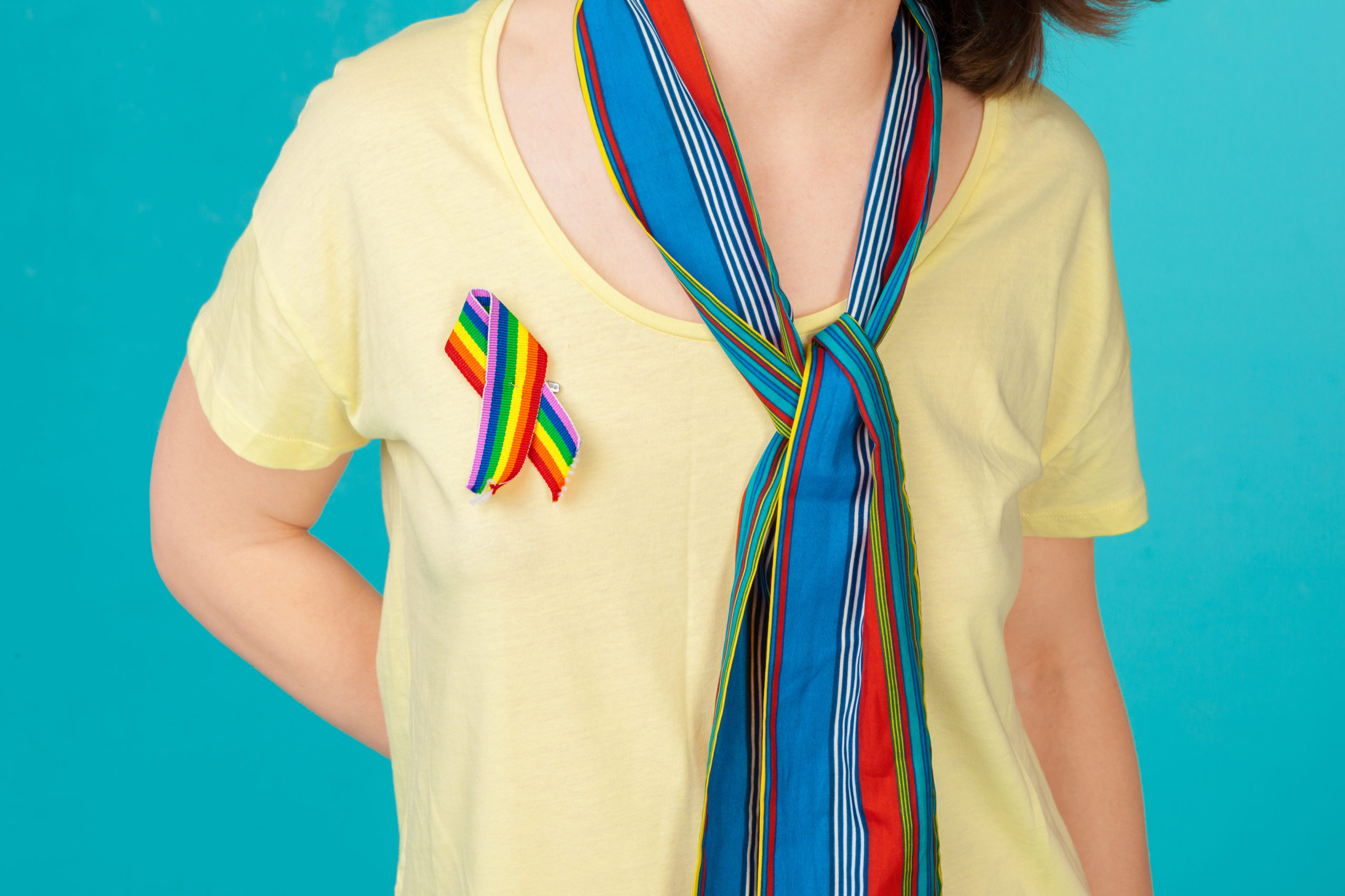 Homosexual and lgbt concept - close up of woman wearing gay pride awareness ribbon on her chest