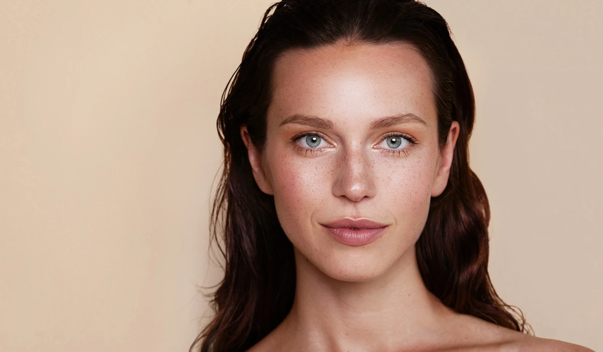 A woman with long brown hair and blue eyes, showcasing her results after Dysport injections